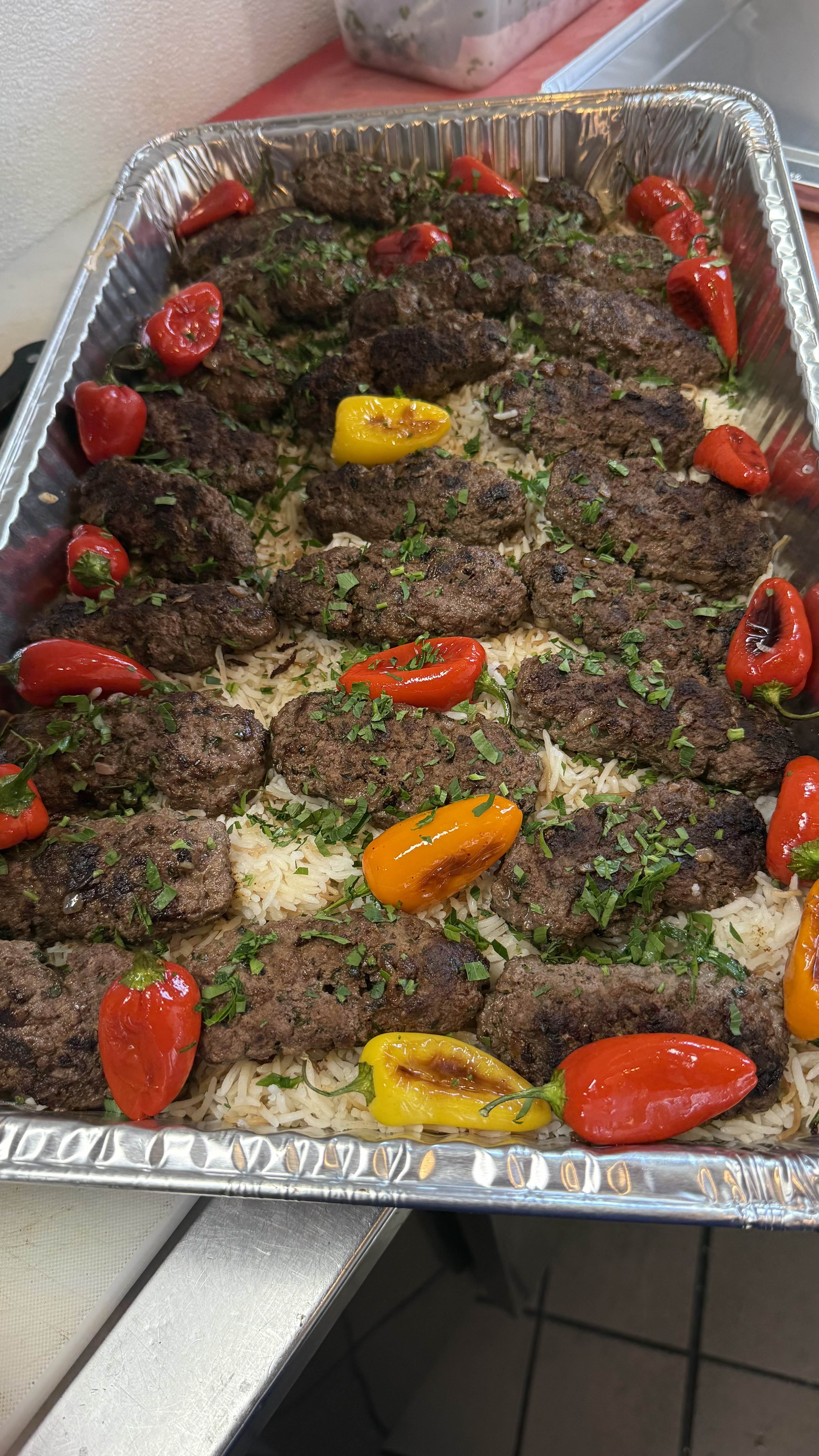 Grilled kafta kebab on fragrant rice with roasted peppers and fresh herbs