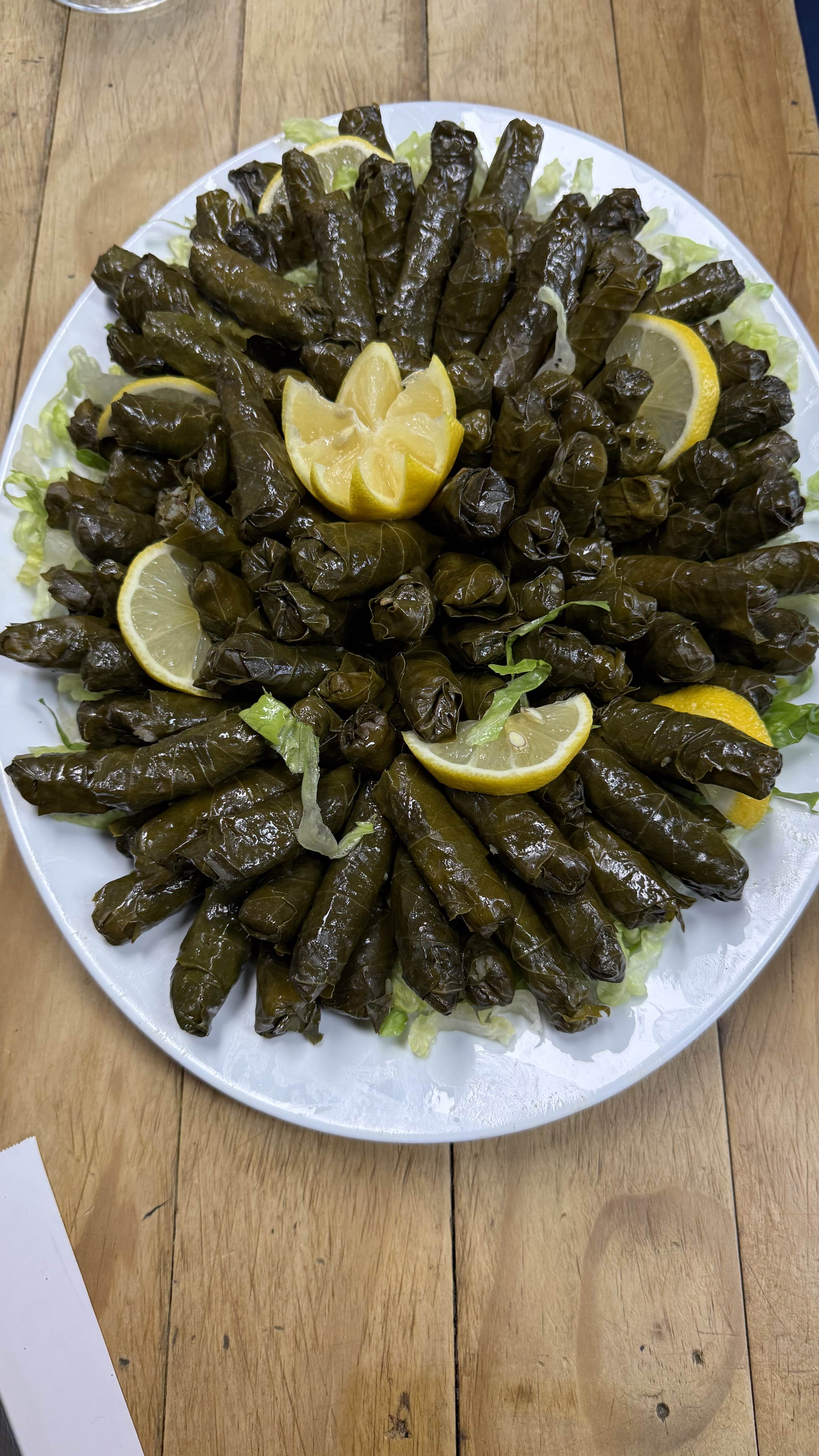 Hand-rolled stuffed grape leaves arranged on a platter with fresh lemon wedges