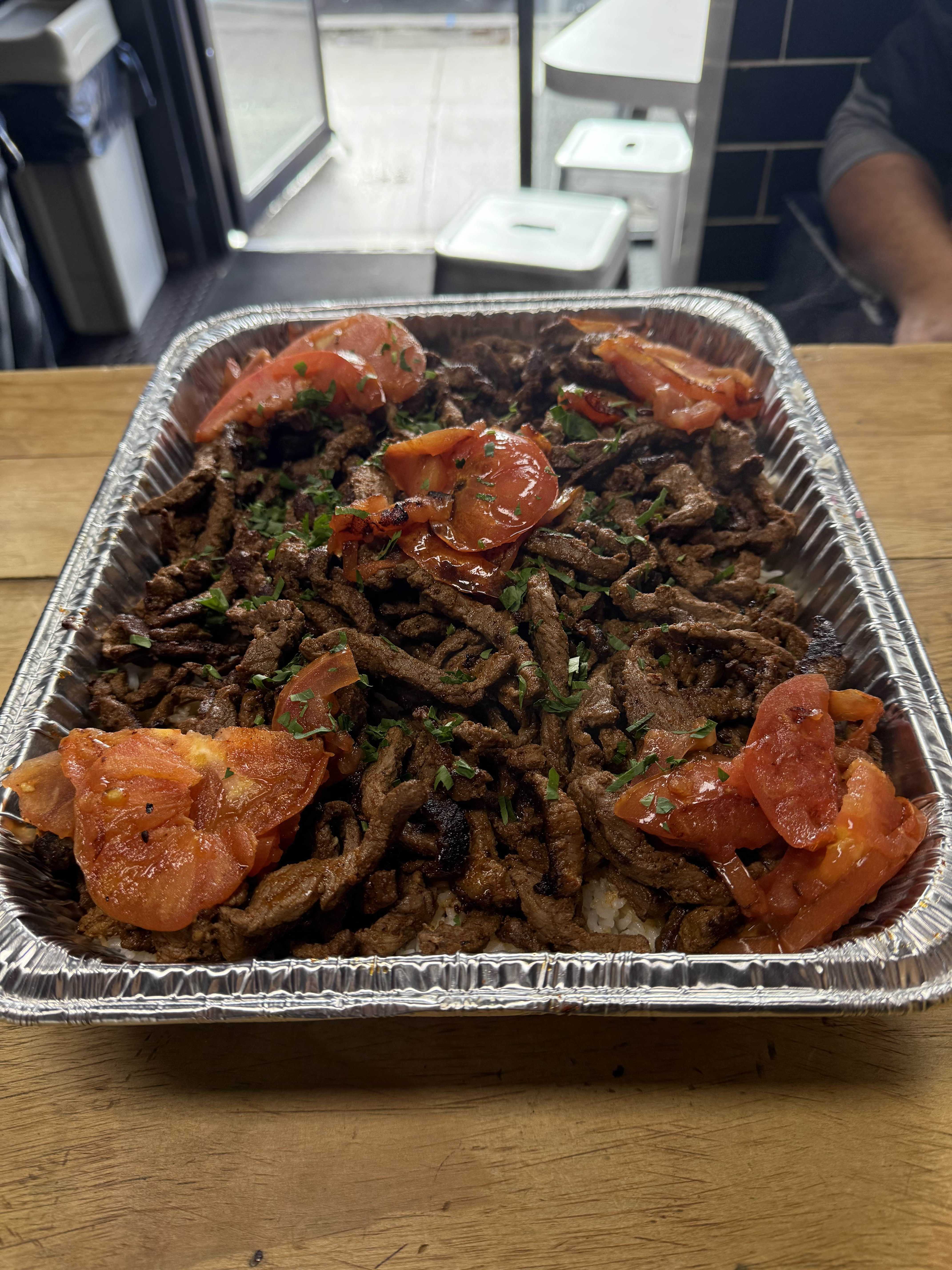 Beef shawarma platter with roasted tomatoes and fresh parsley garnish