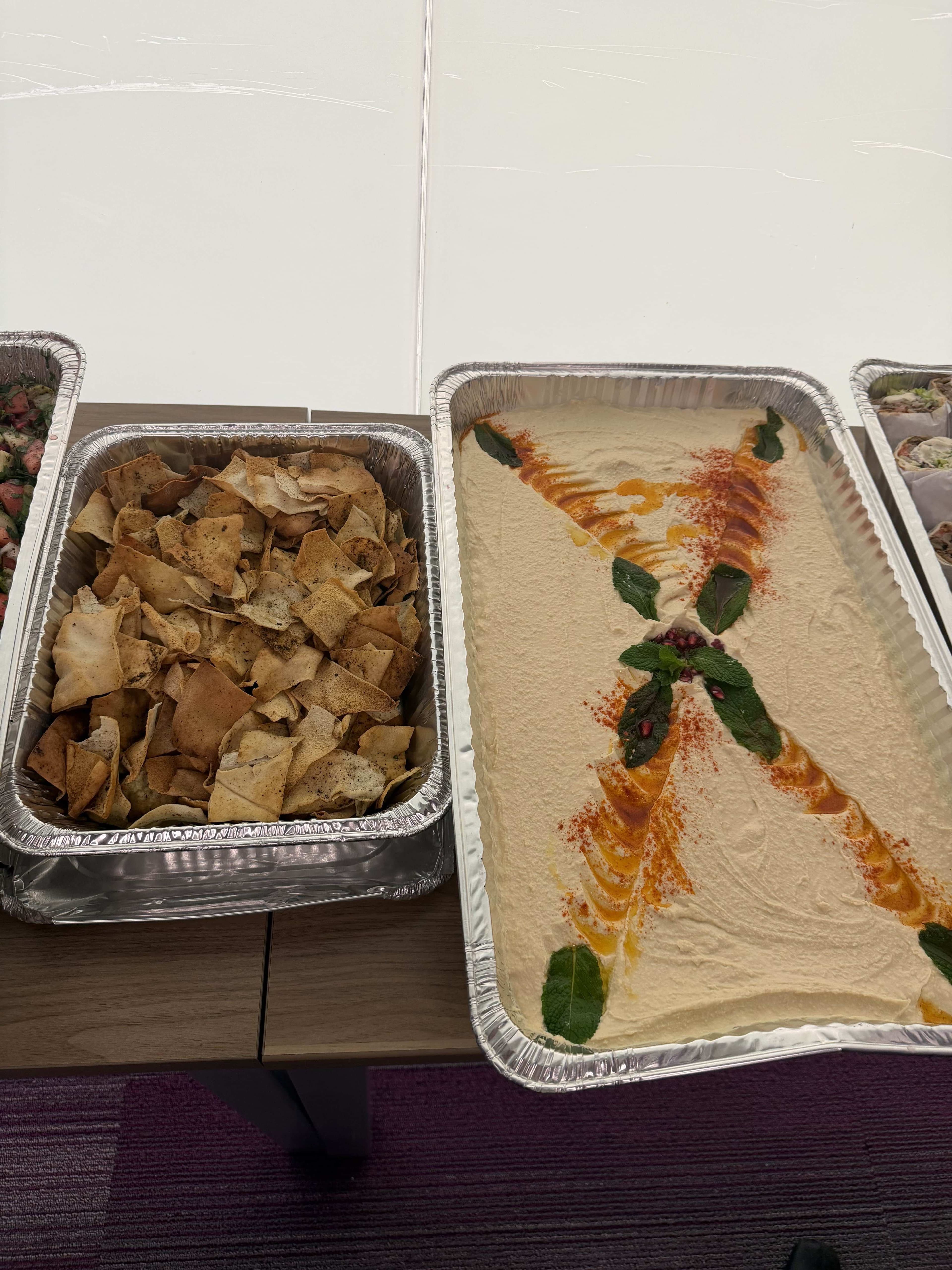 Creamy hummus garnished with olive oil, paprika, and mint served with pita chips