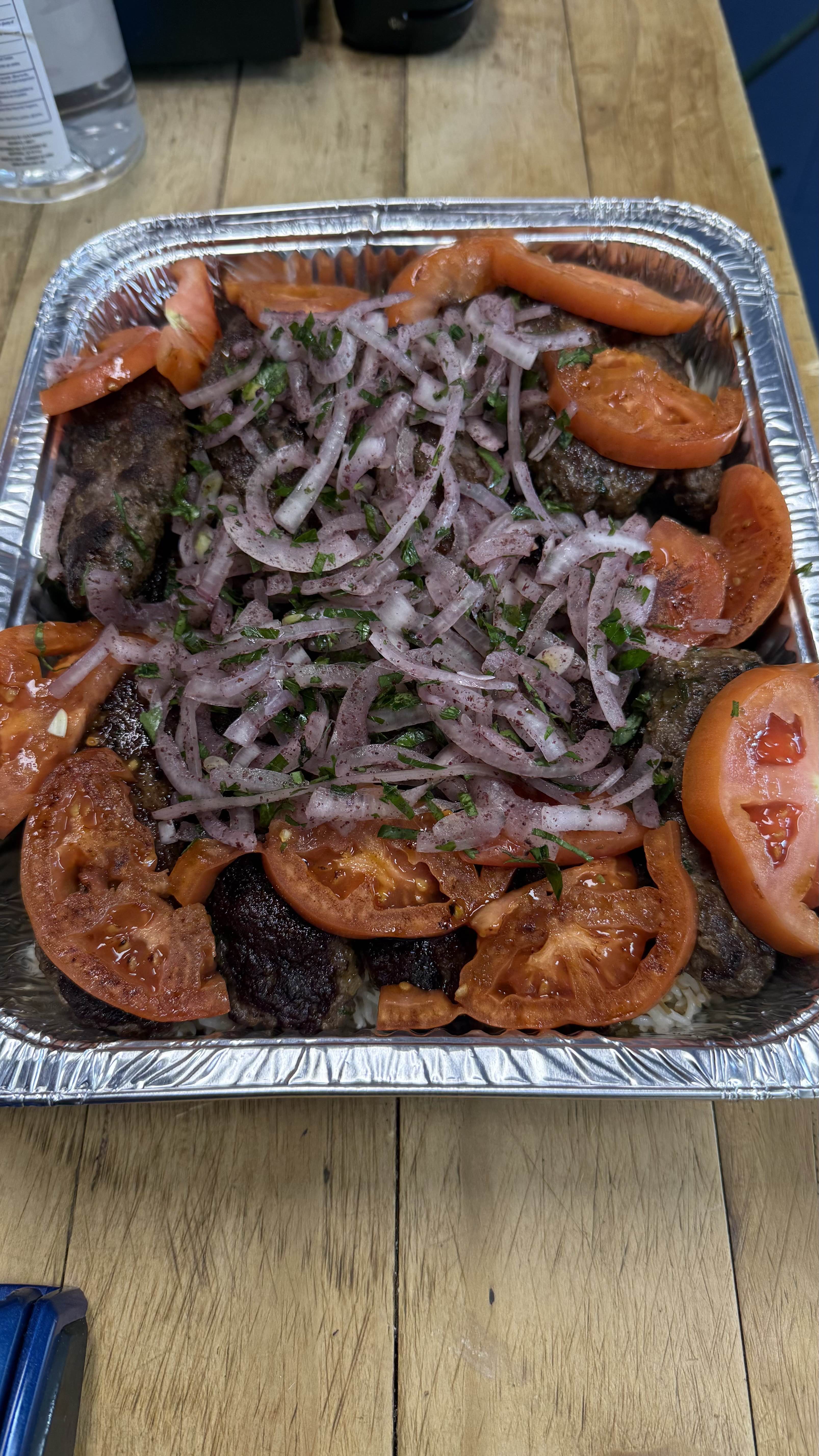 Grilled kebab platter with tomatoes, sumac onions, and rice